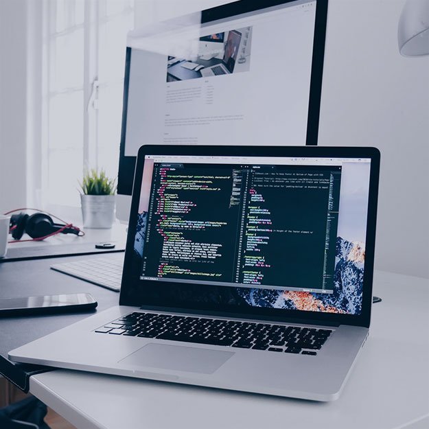 Laptop with coding on screen in a modern workspace.